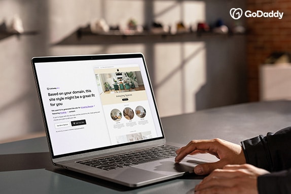Entrepreneur reviewing a website design generated by GoDaddy Airo® on laptop