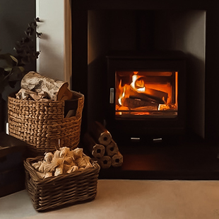 Cosy fireplace with a basket of logs, stacked briquettes and natural firelighters