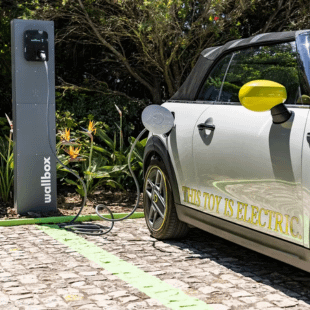 Side profile of an electric MINI charging at a wallbox charging port.