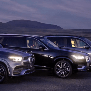 Side view of a silver Mercedes-Benz and a black Volvo.
