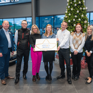 Agnew staff holding an Autism NI Impact Award Champion sign.