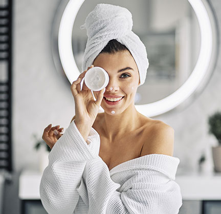 donna in accapatoio con prodotto di bellezza in mano