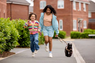 Two children walking a dog in a Four Corners neighbourhood